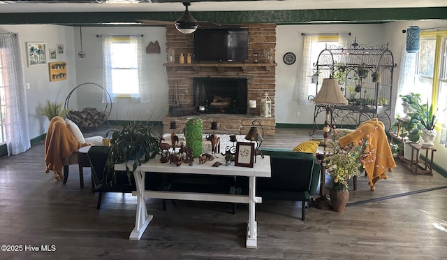 living area with a stone fireplace, baseboards, and wood finished floors