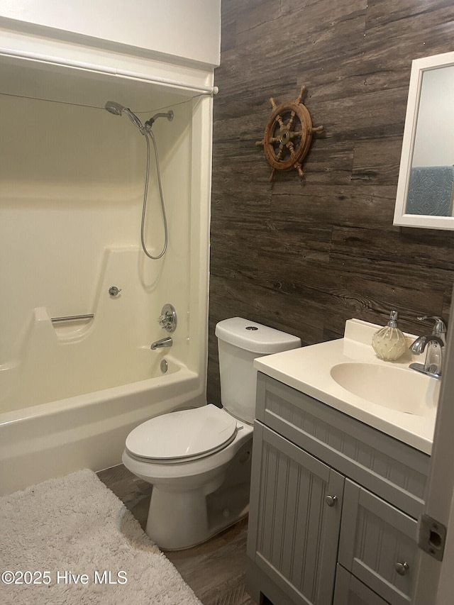 full bathroom featuring bathtub / shower combination, toilet, wooden walls, and vanity