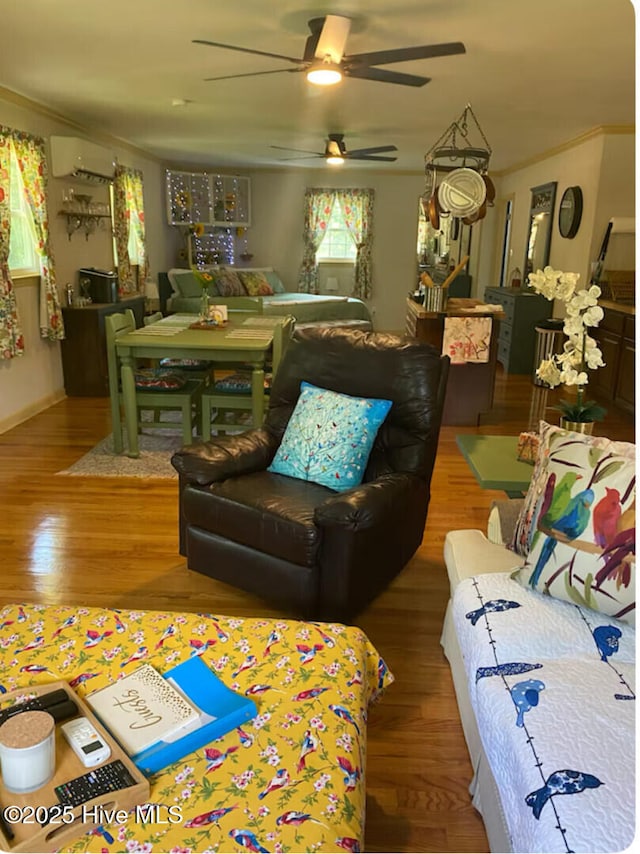 living room featuring a ceiling fan, ornamental molding, wood finished floors, and an AC wall unit