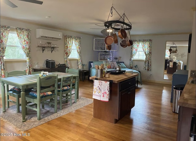 kitchen featuring a ceiling fan, butcher block counters, ornamental molding, an AC wall unit, and light wood-type flooring