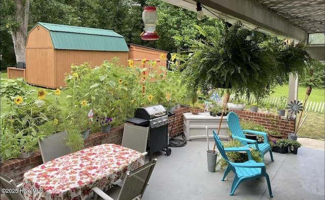 view of patio / terrace with a shed, outdoor dining area, area for grilling, and an outdoor structure