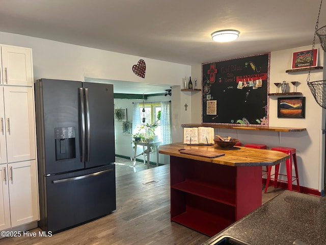 kitchen featuring butcher block counters, white cabinetry, black fridge, open shelves, and dark wood finished floors