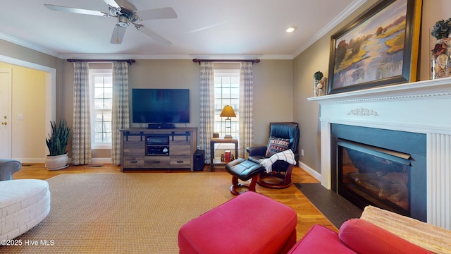 living area with plenty of natural light, a fireplace with flush hearth, crown molding, and wood finished floors