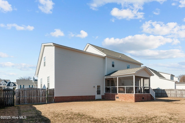 back of property with a sunroom, fence, and a gate