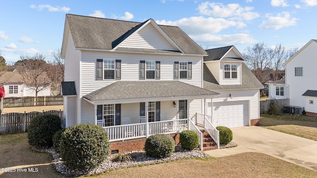 traditional home with roof with shingles, covered porch, fence, a garage, and driveway