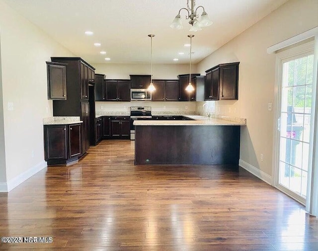 kitchen featuring baseboards, dark wood-type flooring, a peninsula, stainless steel appliances, and light countertops