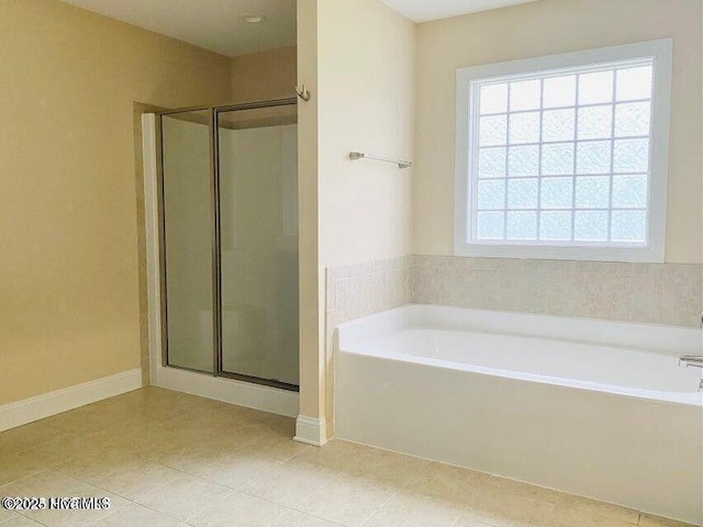 bathroom featuring a garden tub, a shower stall, and baseboards