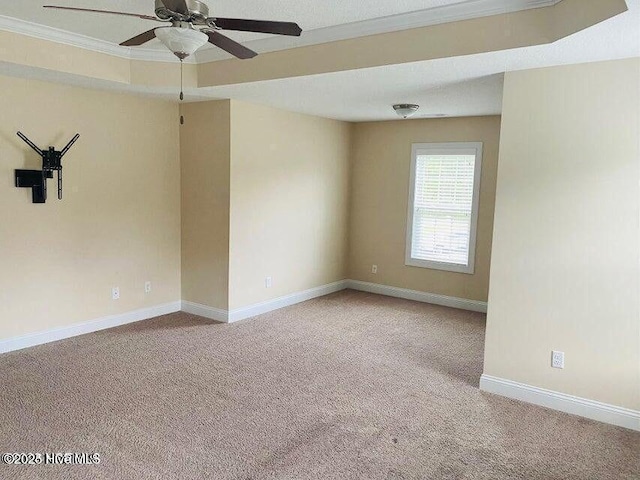 empty room featuring ornamental molding, light carpet, baseboards, and a ceiling fan