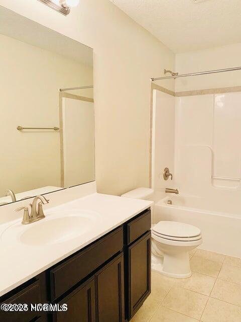 bathroom featuring washtub / shower combination, vanity, tile patterned flooring, and toilet