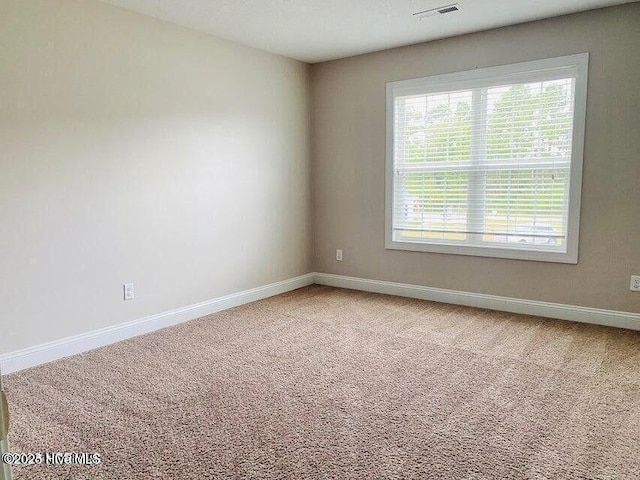 carpeted spare room featuring visible vents and baseboards