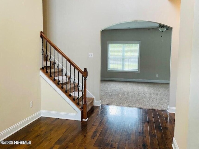 stairway with hardwood / wood-style flooring, baseboards, and arched walkways