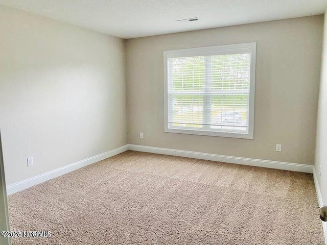 empty room featuring carpet, visible vents, baseboards, and a textured ceiling