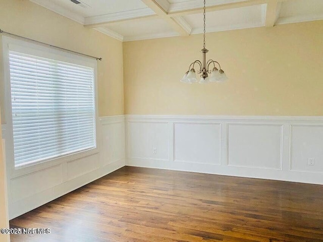 unfurnished dining area featuring coffered ceiling, wood finished floors, wainscoting, beamed ceiling, and an inviting chandelier