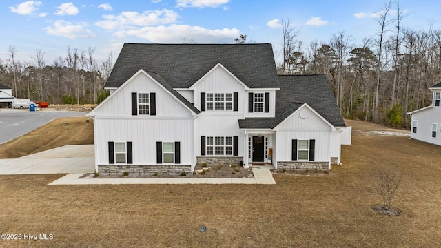 modern farmhouse with driveway, stone siding, a front lawn, and roof with shingles