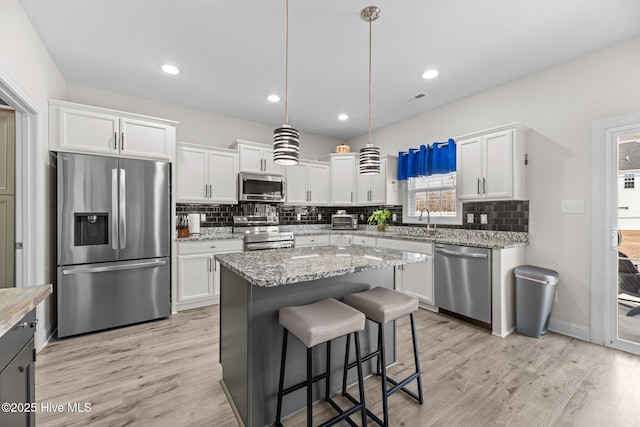 kitchen with light wood-style floors, white cabinetry, appliances with stainless steel finishes, and tasteful backsplash