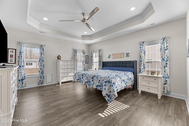 bedroom featuring a tray ceiling, wood finished floors, visible vents, and crown molding