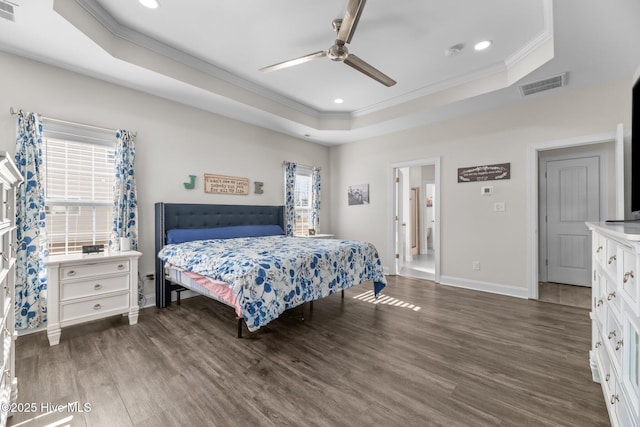 bedroom with ornamental molding, a raised ceiling, visible vents, and wood finished floors