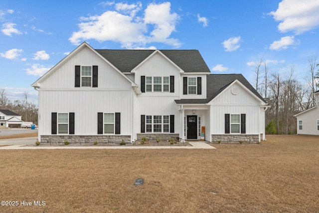 modern farmhouse featuring board and batten siding, stone siding, roof with shingles, and a front lawn