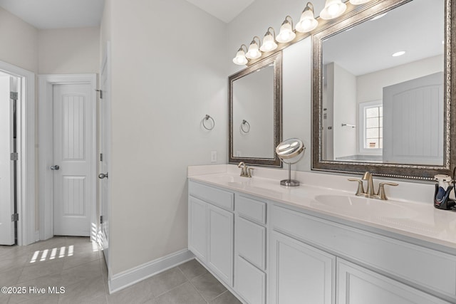 bathroom with double vanity, baseboards, a sink, and tile patterned floors