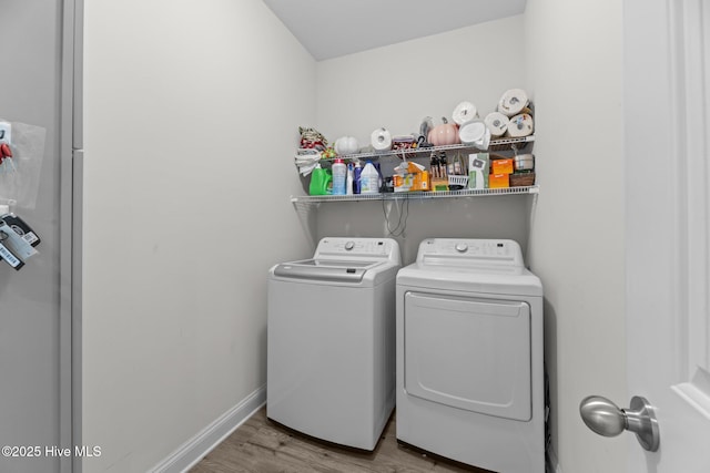 clothes washing area featuring laundry area, washer and clothes dryer, wood finished floors, and baseboards