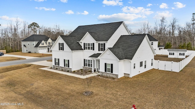 modern farmhouse style home with a gate, roof with shingles, fence, and a front lawn