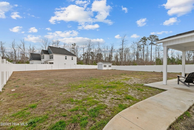 view of yard featuring an outbuilding, a fenced backyard, a patio, and a storage unit