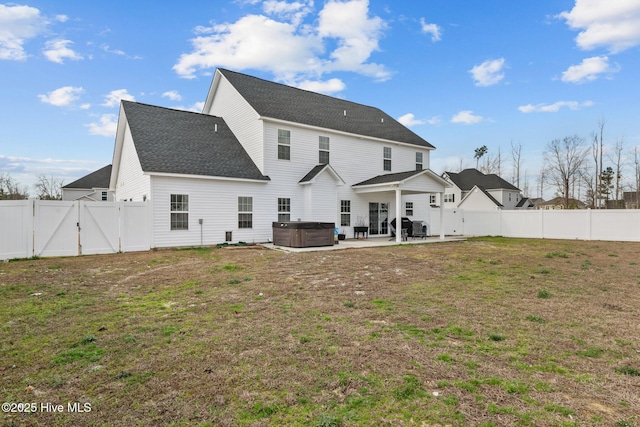 rear view of house featuring a patio, a fenced backyard, a gate, and a hot tub