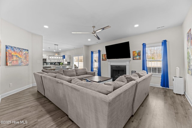 living room with recessed lighting, baseboards, a fireplace, and light wood finished floors