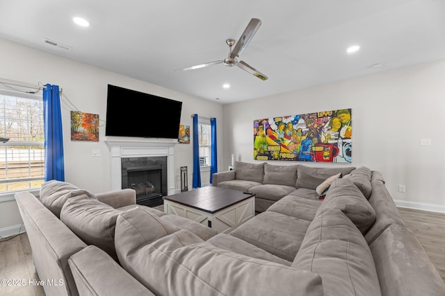 living room with recessed lighting, visible vents, light wood-style flooring, and a tiled fireplace