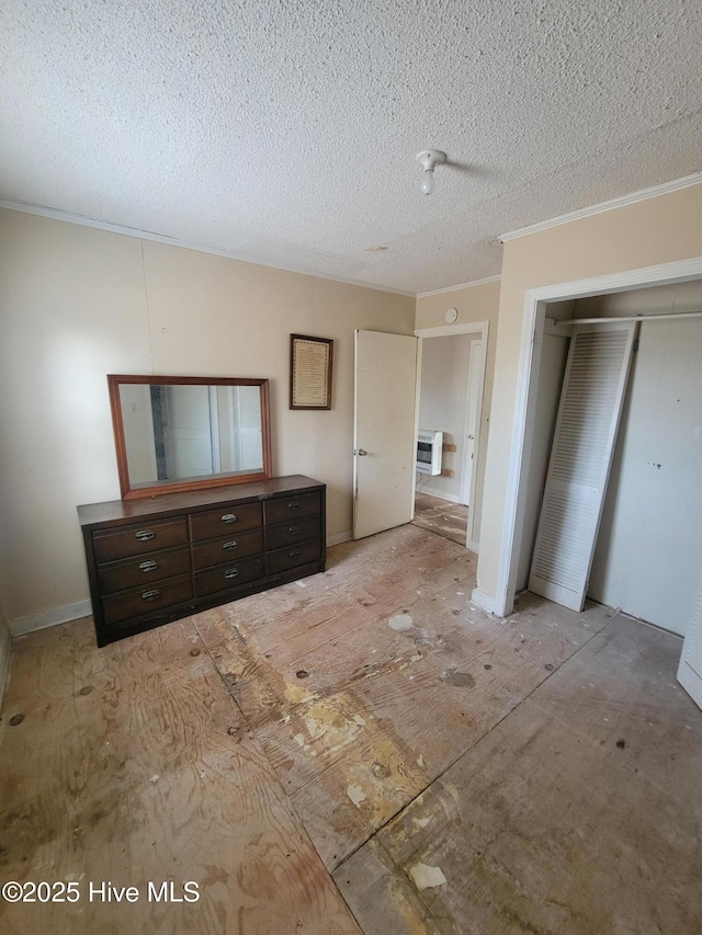 unfurnished bedroom with ornamental molding, a closet, a textured ceiling, and baseboards