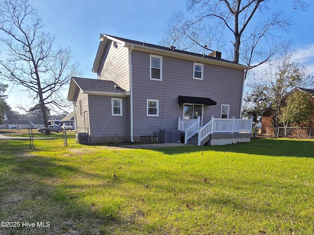 back of property with a wooden deck, a lawn, a chimney, and fence