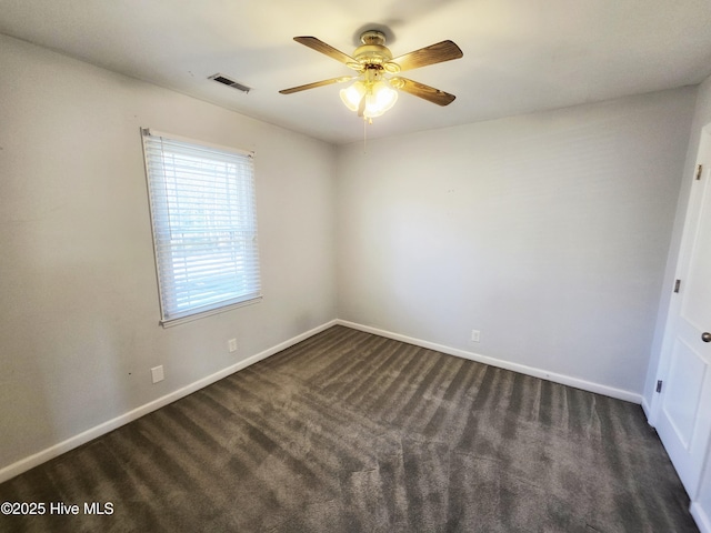unfurnished room featuring baseboards, visible vents, dark carpet, and ceiling fan