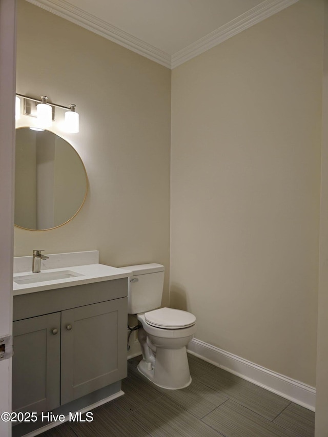 bathroom with vanity, toilet, crown molding, and baseboards