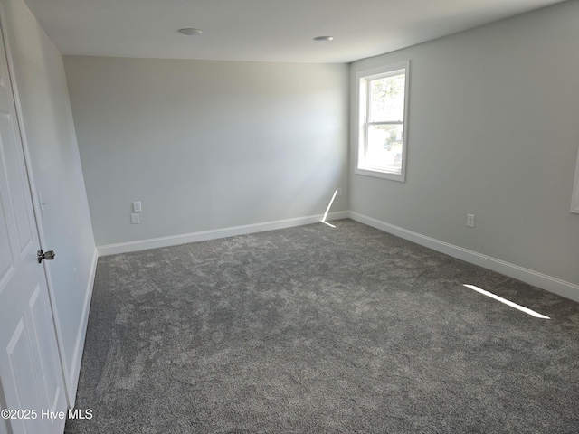 empty room with baseboards and dark carpet