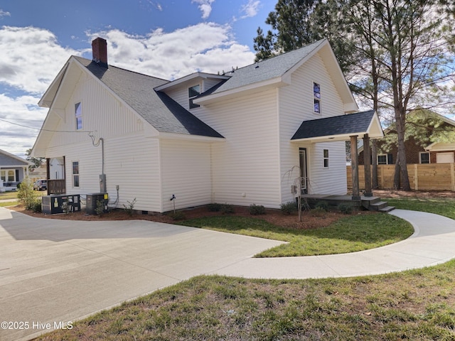 view of property exterior with roof with shingles, a chimney, central AC unit, crawl space, and fence