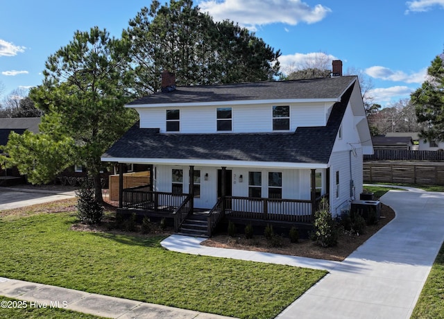 view of front of property featuring a shingled roof, a front yard, covered porch, and a chimney