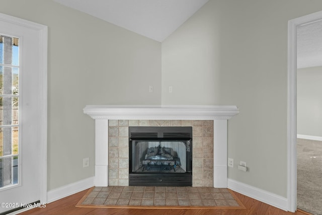 room details with baseboards, a tiled fireplace, and wood finished floors