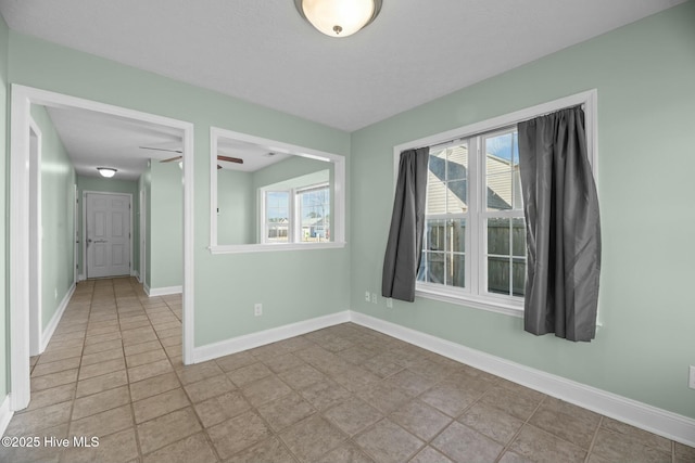 spare room with ceiling fan and baseboards