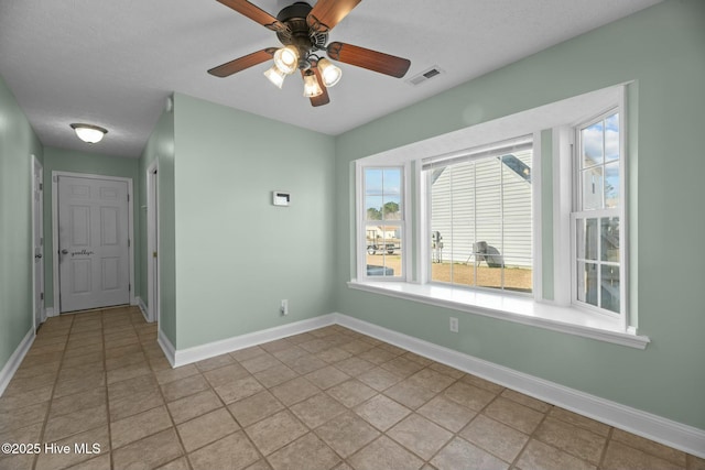 empty room featuring baseboards, visible vents, and a ceiling fan