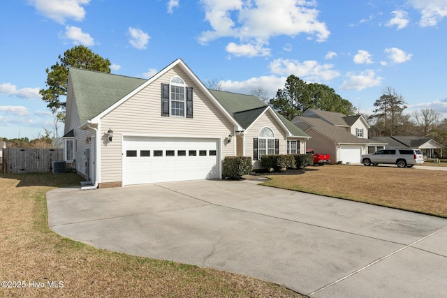 traditional-style home featuring a shingled roof, concrete driveway, fence, a garage, and a front lawn