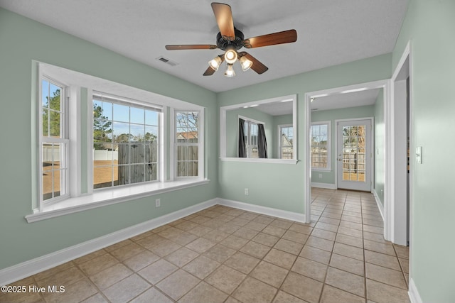 spare room with a ceiling fan, light tile patterned flooring, visible vents, and baseboards