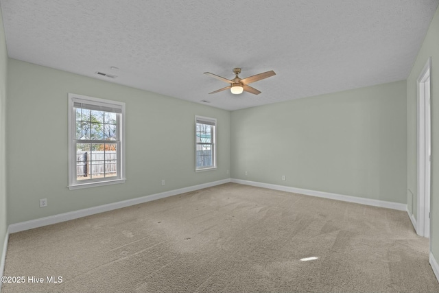 unfurnished room with a textured ceiling, ceiling fan, visible vents, baseboards, and carpet