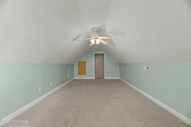 bonus room featuring a textured ceiling, lofted ceiling, carpet flooring, visible vents, and baseboards