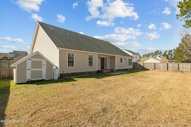 rear view of property featuring a fenced backyard, a storage unit, a lawn, and an outbuilding