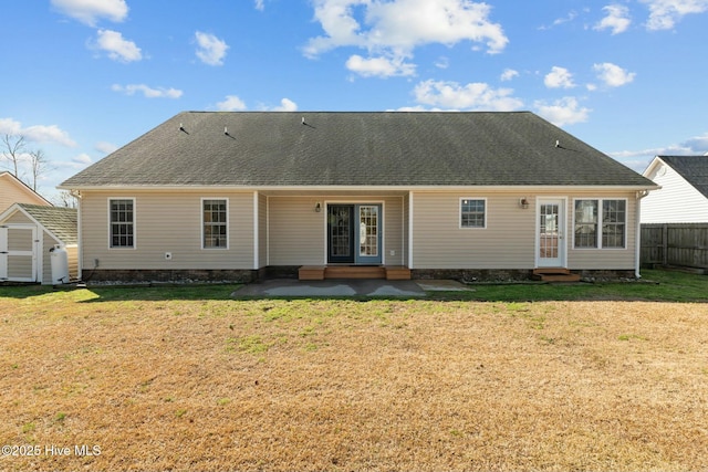 back of house with entry steps, a patio area, fence, and a lawn