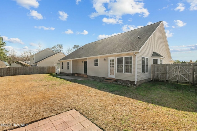 back of house featuring entry steps, a patio, a fenced backyard, a shingled roof, and a lawn