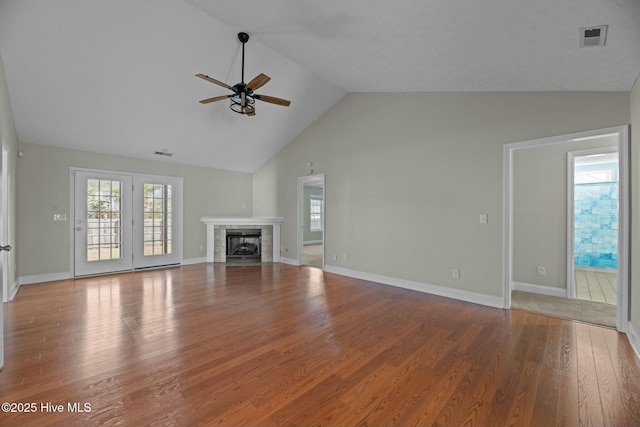 unfurnished living room featuring ceiling fan, a fireplace, wood finished floors, and visible vents