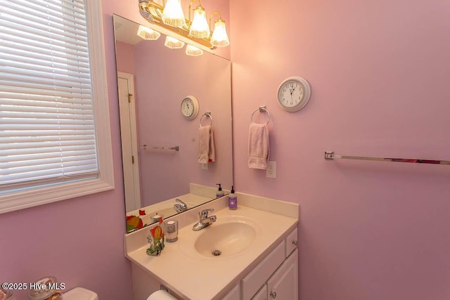 half bath featuring toilet, vanity, and a notable chandelier