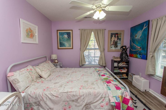 bedroom featuring a textured ceiling, wood finished floors, a ceiling fan, and baseboards