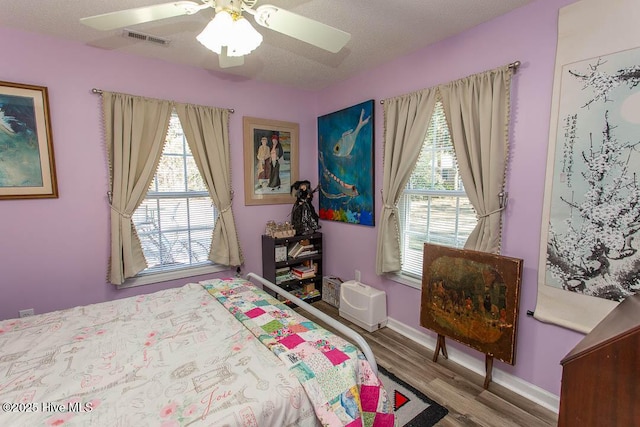 bedroom with baseboards, visible vents, ceiling fan, and wood finished floors